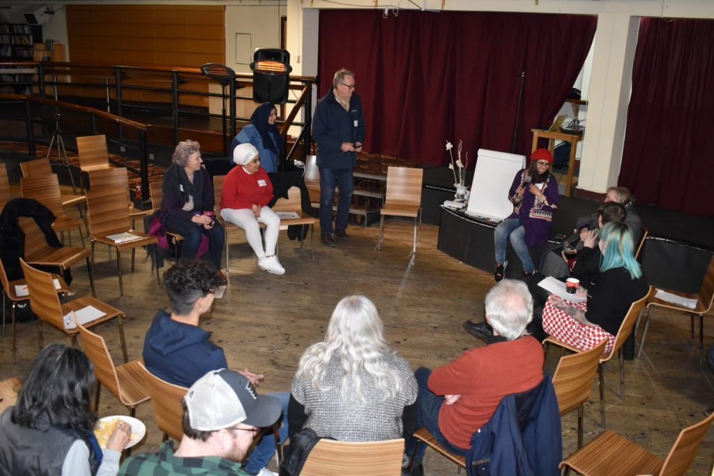 An overhead photo of a group of people sat in a circle talking.