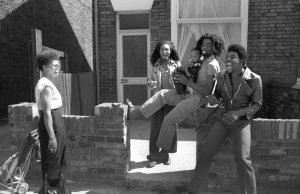A black and white photo of a family sat on a brick fence.