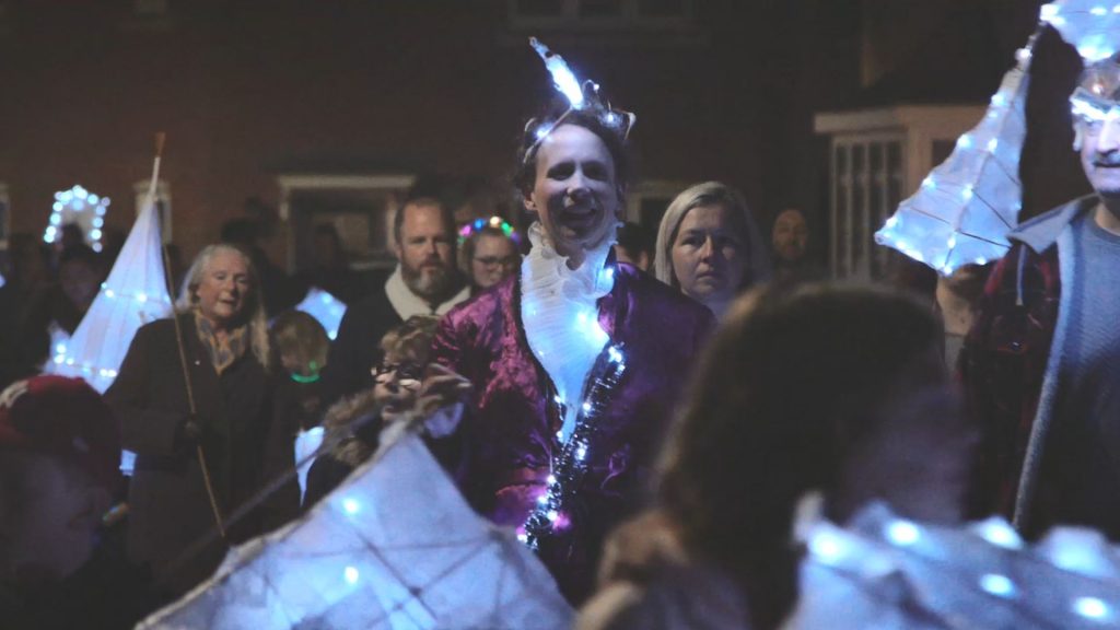Crowd of people in the dark - some holding their glowing lanterns