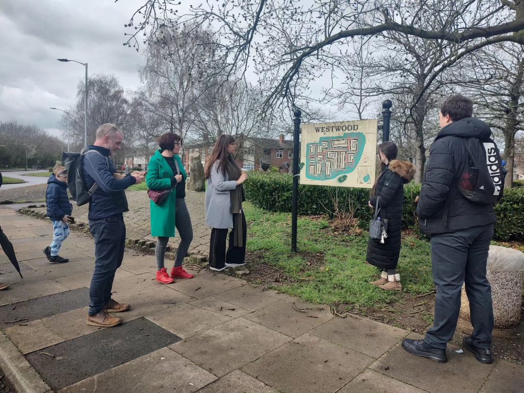 From left to right, Keith, Nikki, Sam, Laura, and Ryan are stood on a footpath in Westwood, looking at the neighbourhood map.