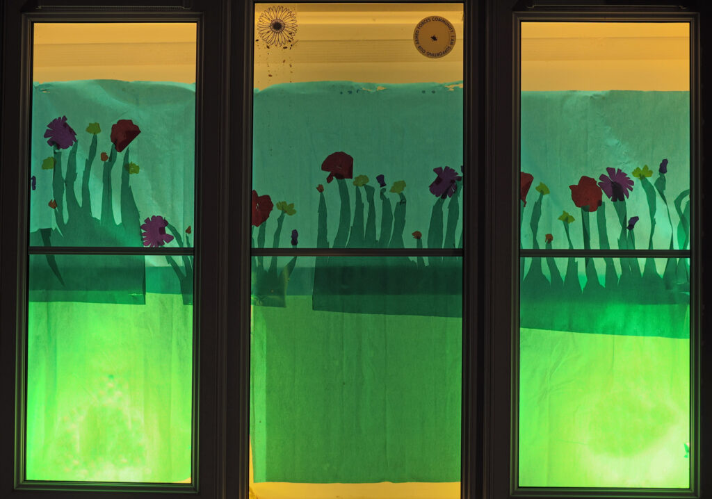 A nature scene window with green across the bottom and flowers in the middle and blue across the top.