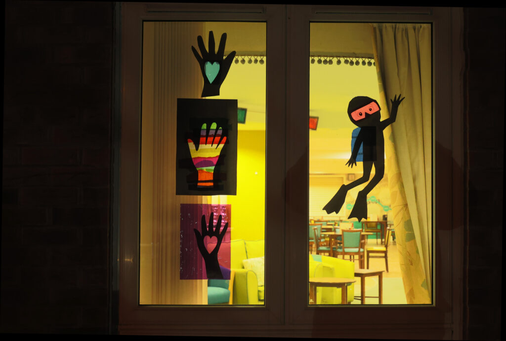 A simple window design with silhouettes of hands on the left and a scuba diver waving on the right.