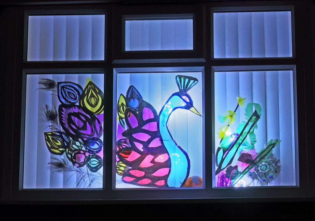 A close up of a front window. A bluey coloured Peacock design over 3 windows.