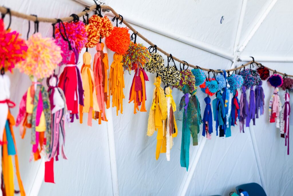 In the Creative dome at the Peterborough Celebrated Festival.... A close-up of the super colourful pom pom fabric bunting handing accross the walls of the creative dome... made by Artist Rose Croft and the local communicat groups.
