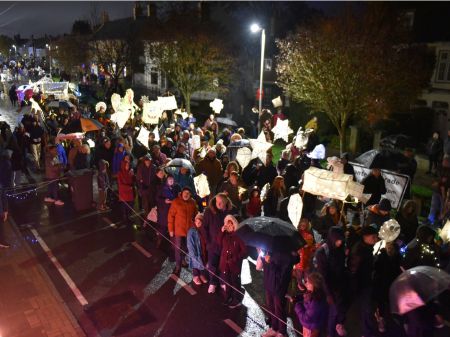 Top down view of crowds of people in the lantern parade, There are several hand made lanterns in view in various shapes and sizes, all lit from within.