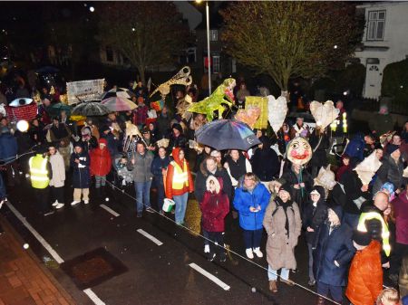 Top down view of crowds of people in the lantern parade, There are several hand made lanterns in view in various shapes and sizes, all lit from within.