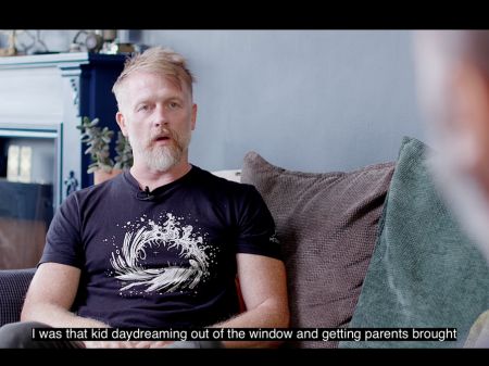 Lee Mason being interviewed for Jay's film. Lee is looking to the right and mid-conversation. Lee is a white man with blonde hair and beard, wearing a black t-shirt.