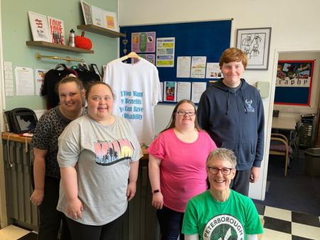 Sarah poses with members of 3 members The Helping Hands Group, a charity supporting learning disabled young people. Behind the group is a t-shirt from the protest t-shirt trail.
