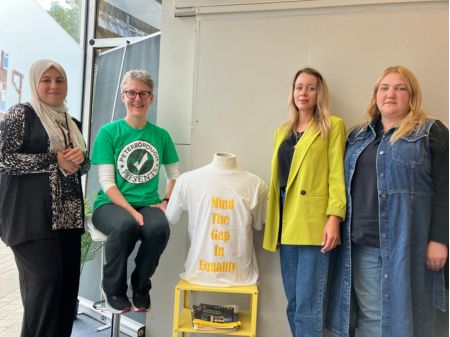 Sarah poses with members of 3 members of HELP, a charity supporting refugee and asylum seekers. In the middle of the group is a t-shirt from the protest t-shirt trail.