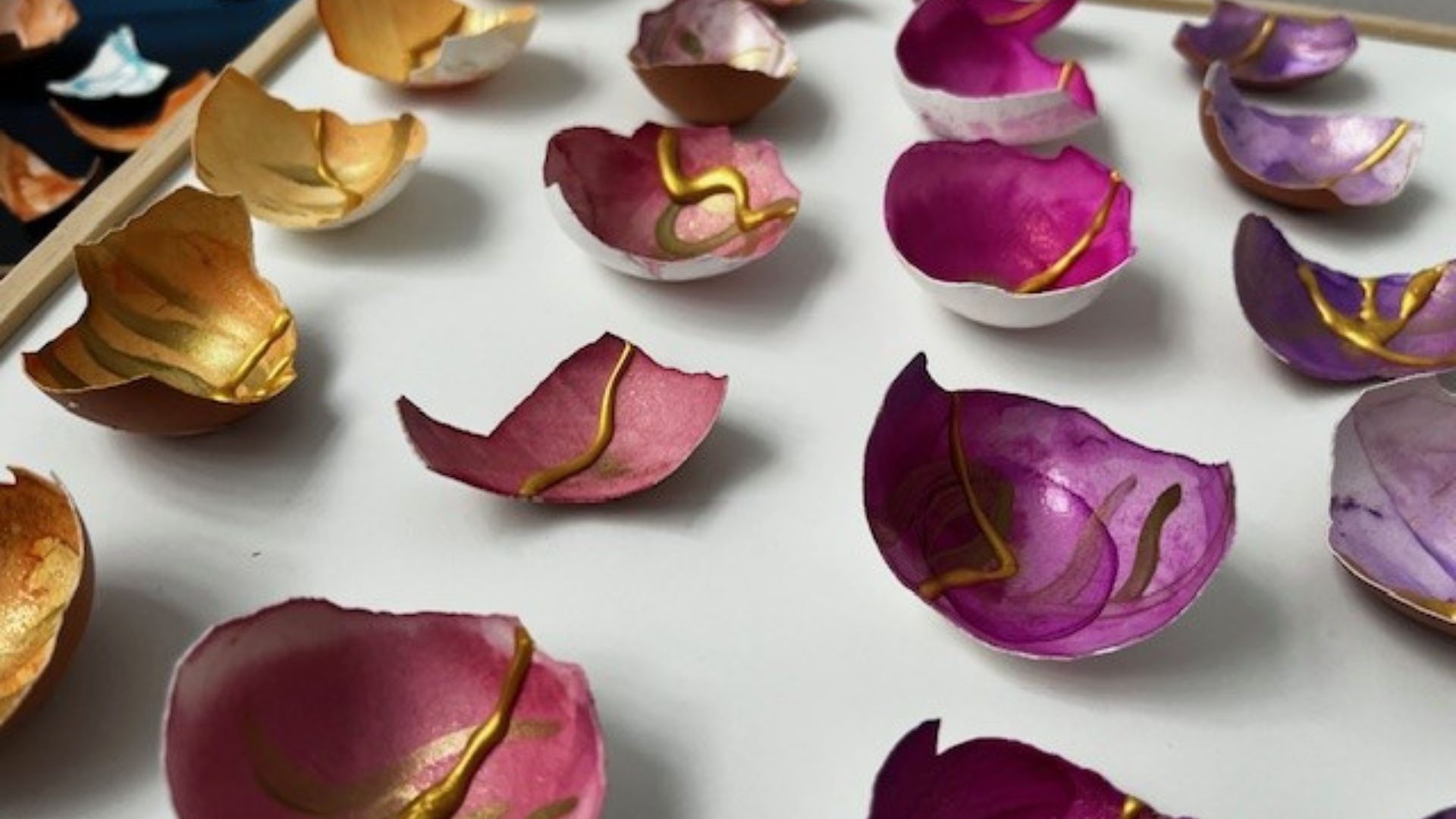 Creative Workshop for Muslim SEND mums Close up of fractured colourful bowls in purples, pink, orange and yellow that have been decorated in gold lines, used to repair the bowl.